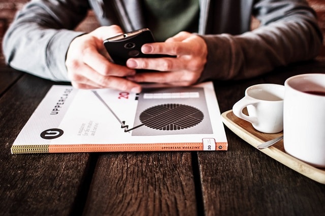 man-at-desk-scrolling-on-smartphone-illustrates-email-contact-list